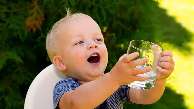 Kind mit Wasserglas Babys richtig vor Hitze schützen