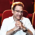 Benjamin Eisenberg sitzt in einem roten Theatersessel und blickt in die Kamera